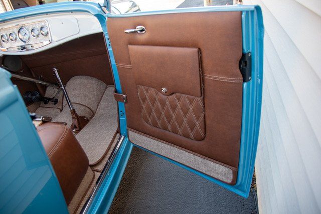 Open, light blue car door with brown interior, diamond-stitched pocket.