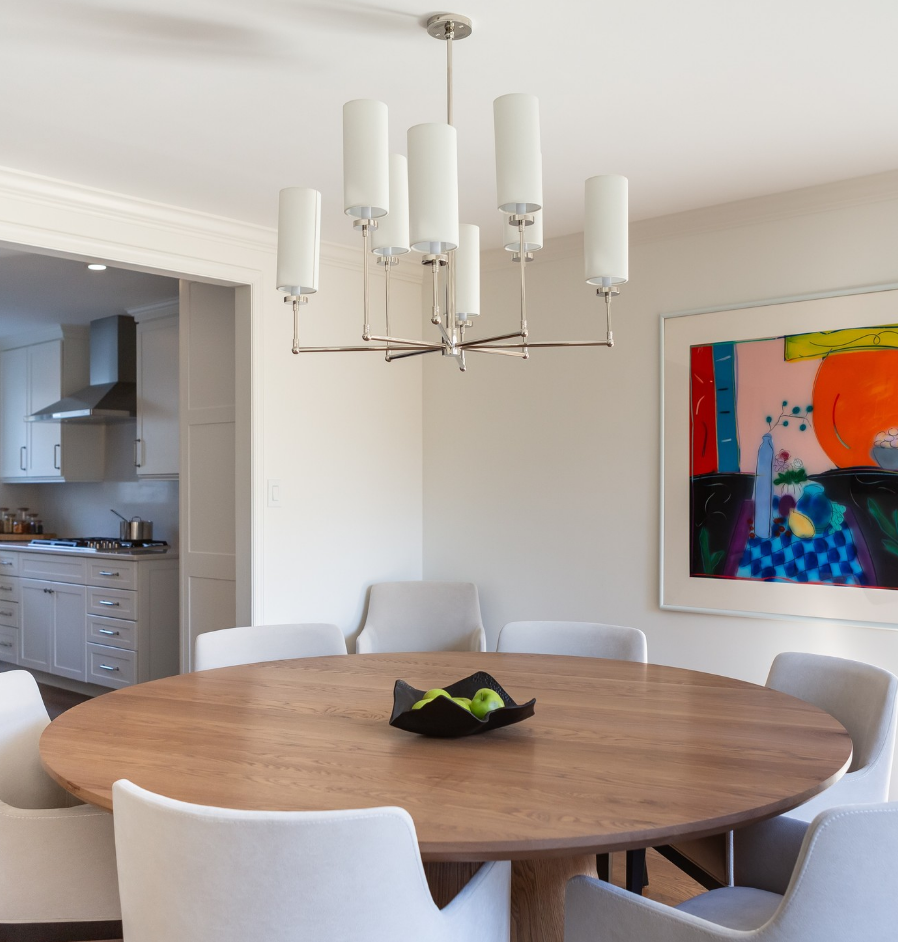 A dining room with a round table and white chairs