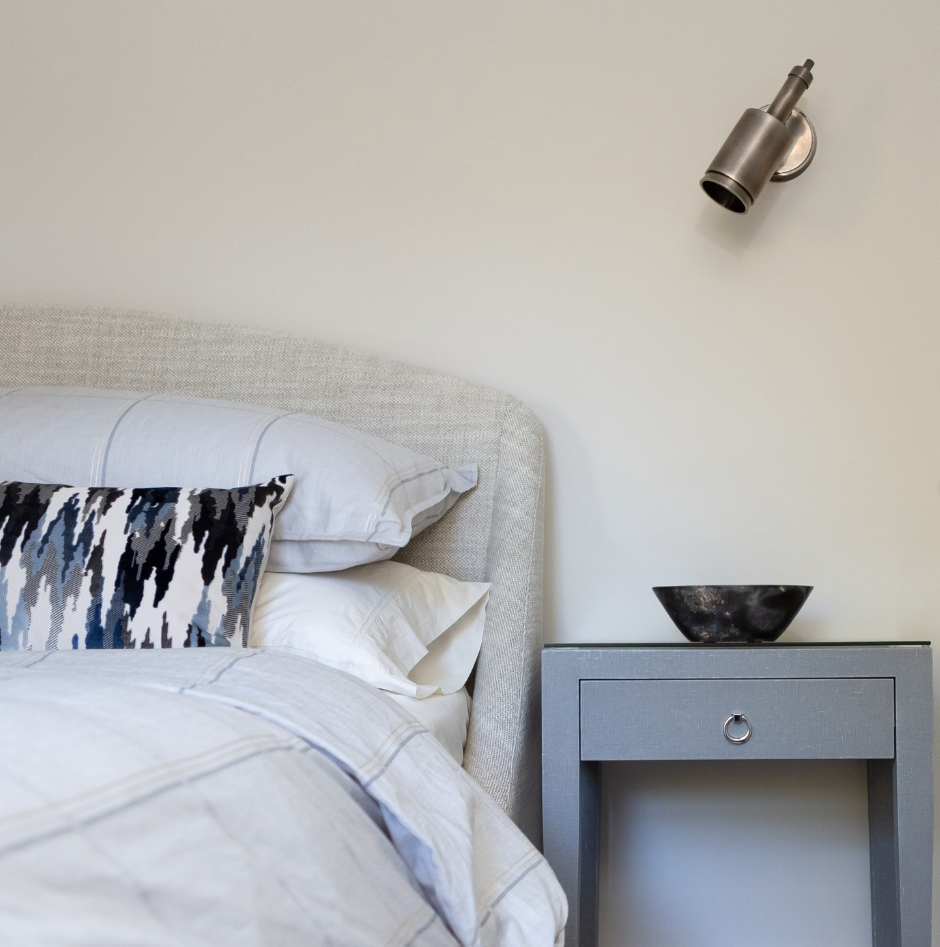 A bedroom with a bed and a nightstand with a bowl on it