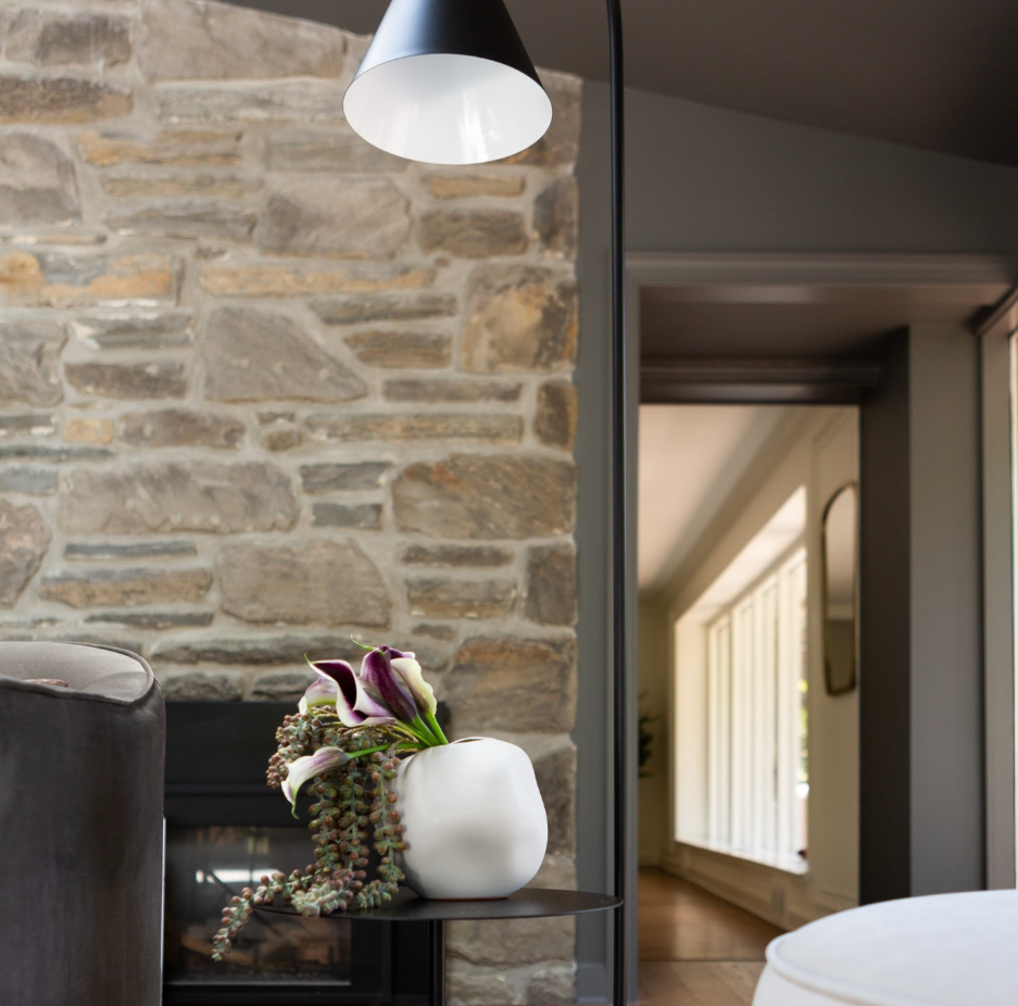 A vase of flowers sits on a shelf in front of a stone wall