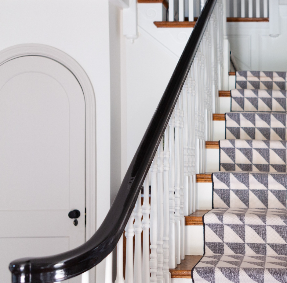 A staircase with a patterned carpet and a black railing