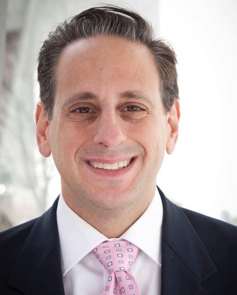 A man in a suit and tie is smiling for the camera