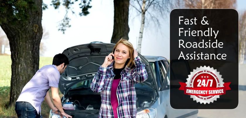 A man and a woman are standing next to a broken down car. A caption says