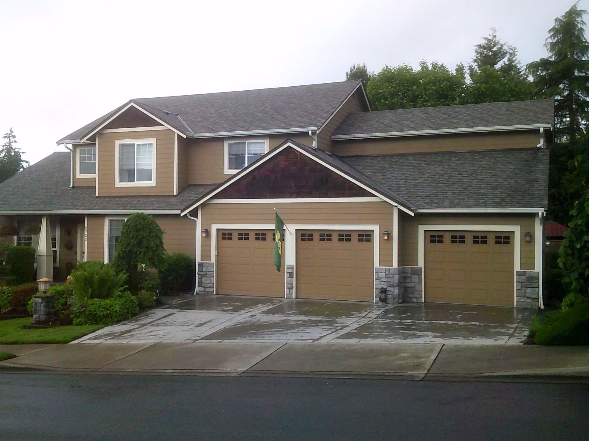 A large house with three garage doors and a gray roof