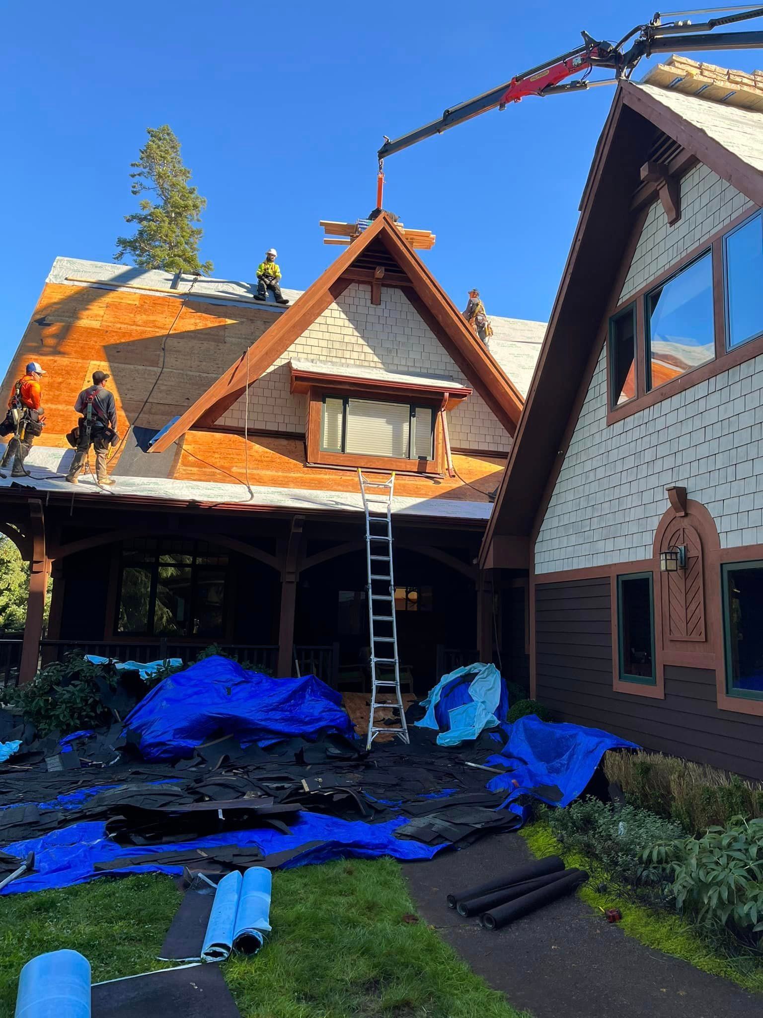 A large house is being remodeled with a crane on the roof.