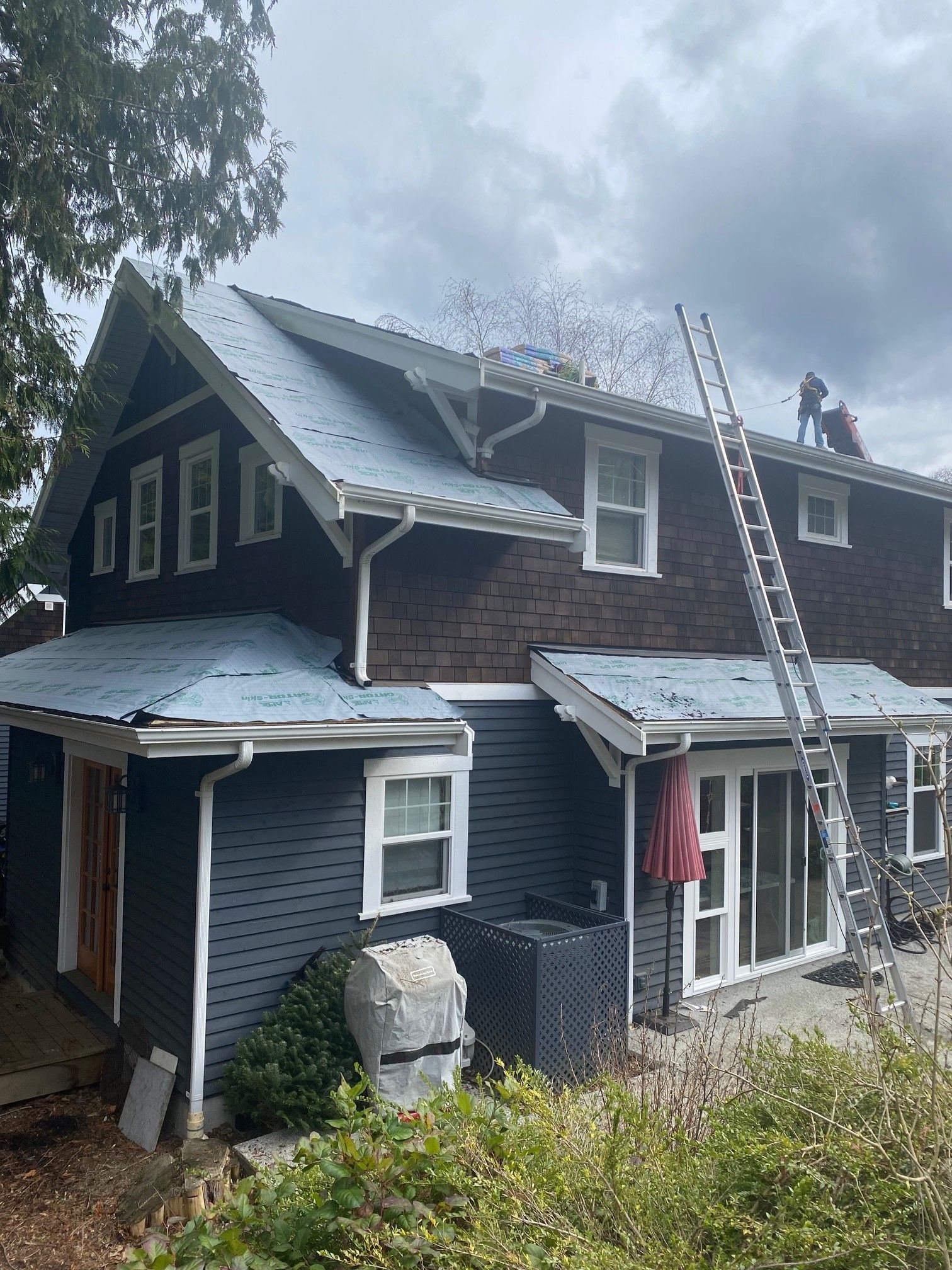 A couple of people are working on the roof of a house.