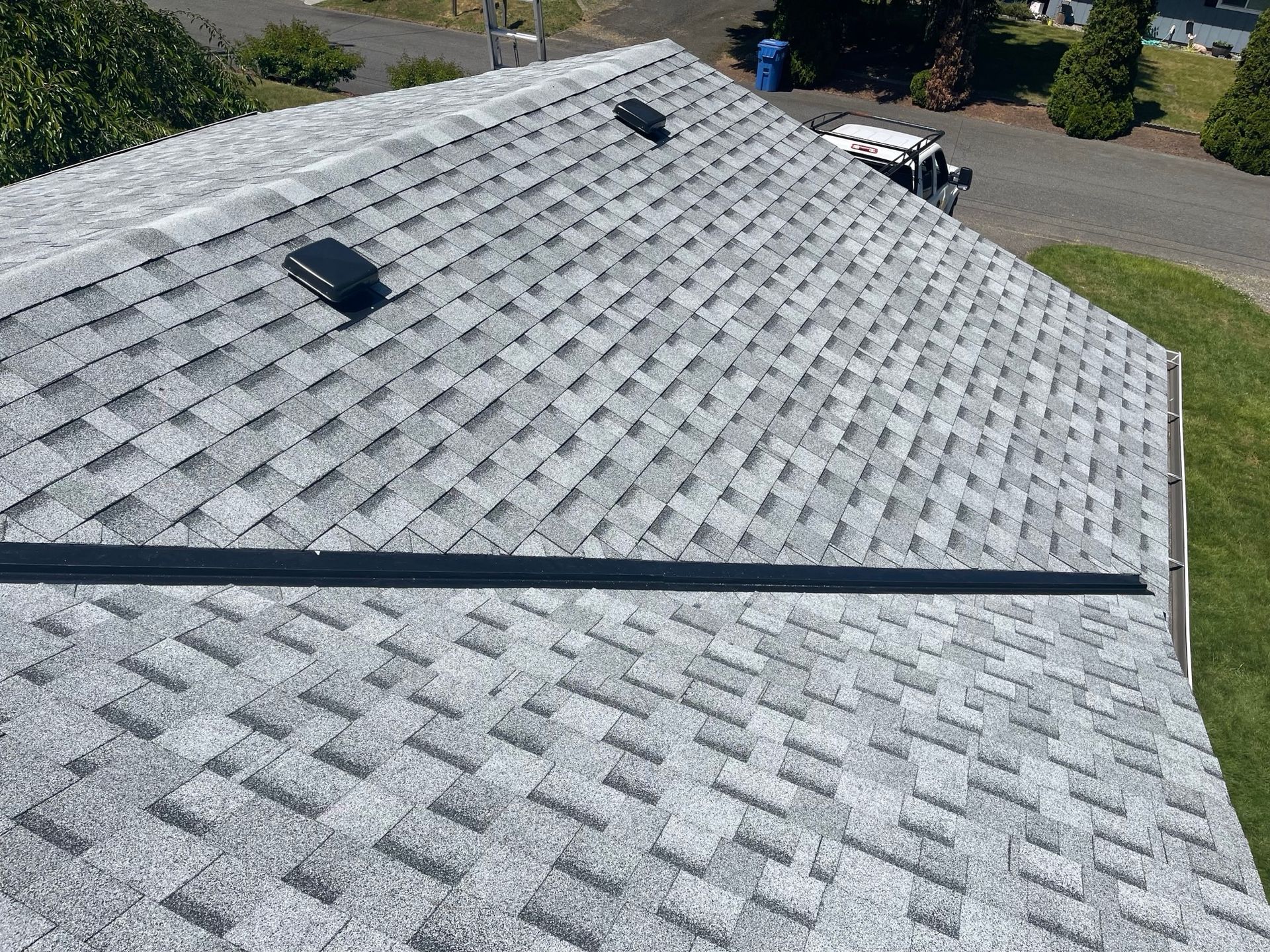 A roof with a lot of shingles on it is sitting on top of a house.