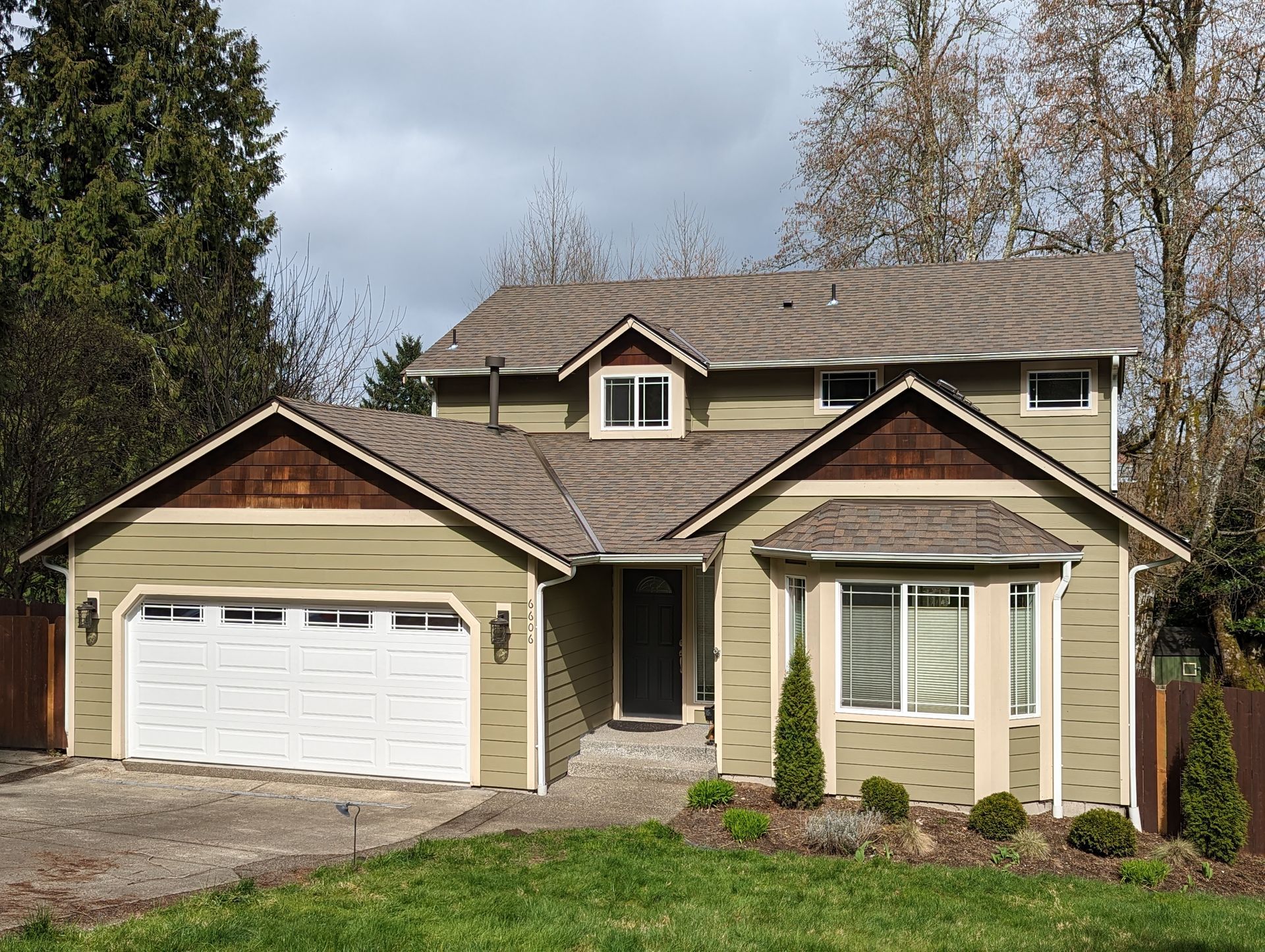 A large house with two garage doors and a large lawn in front of it.