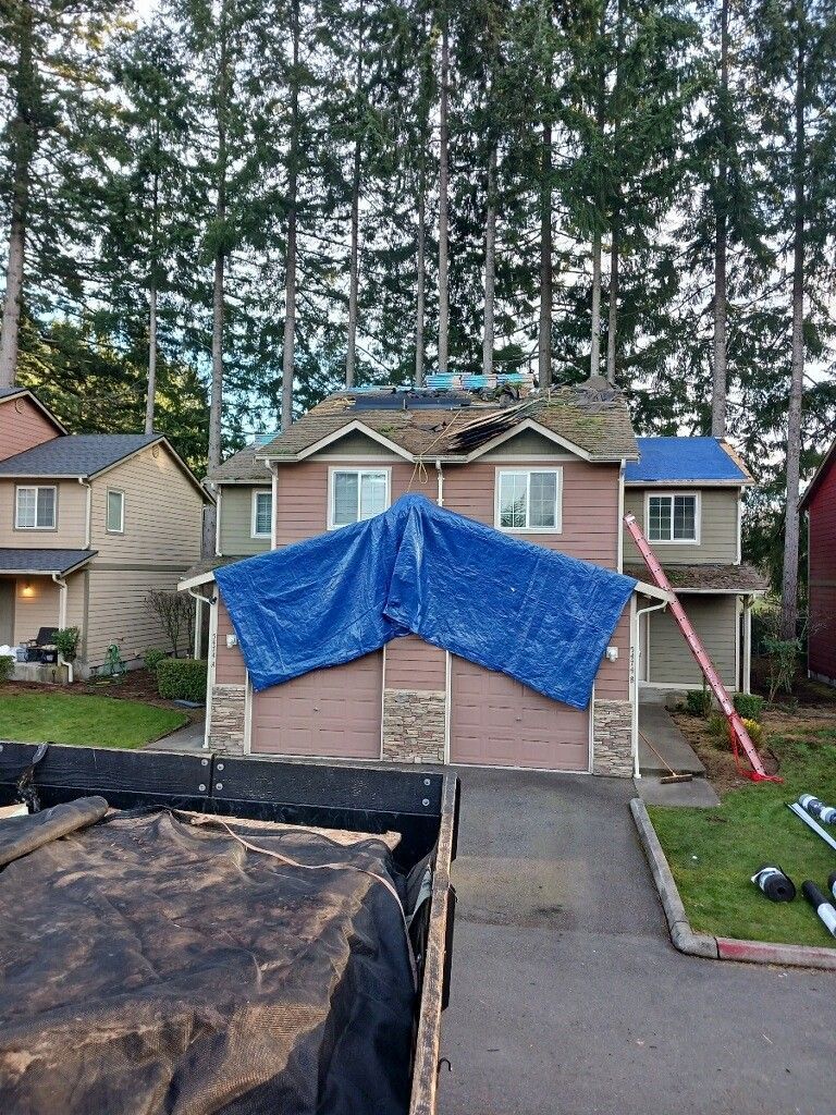 A house with a blue tarp on top of it.