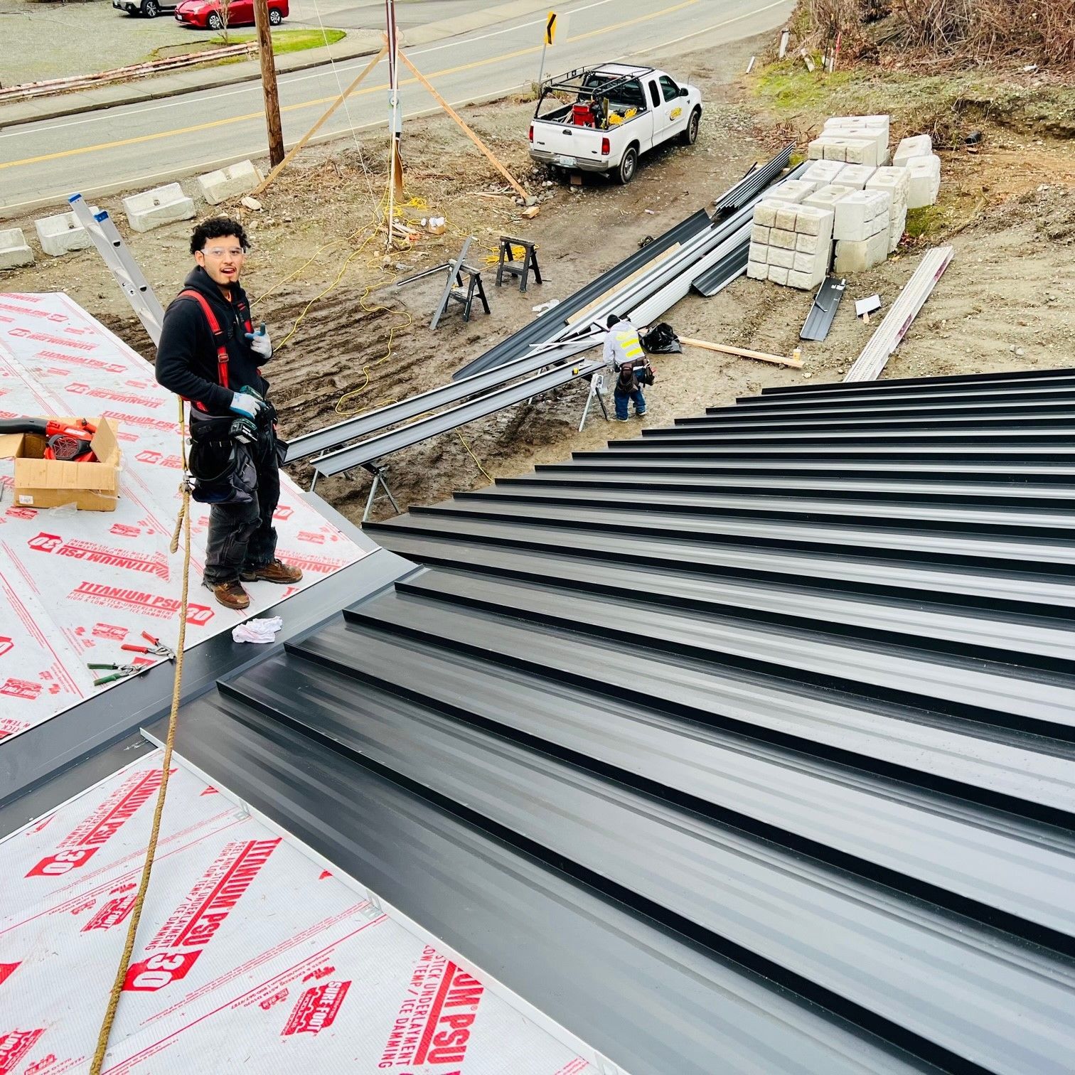 A man is standing on top of a metal roof.