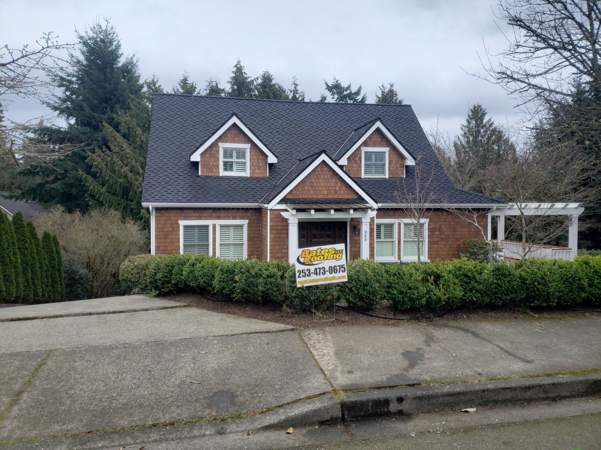 A brick house with a black roof and a sign in front of it.