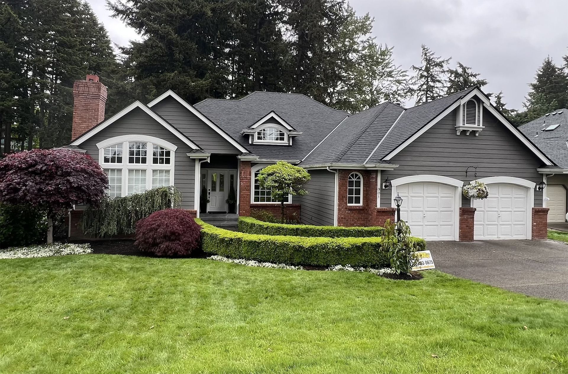 A large house with two garages and a lush green lawn