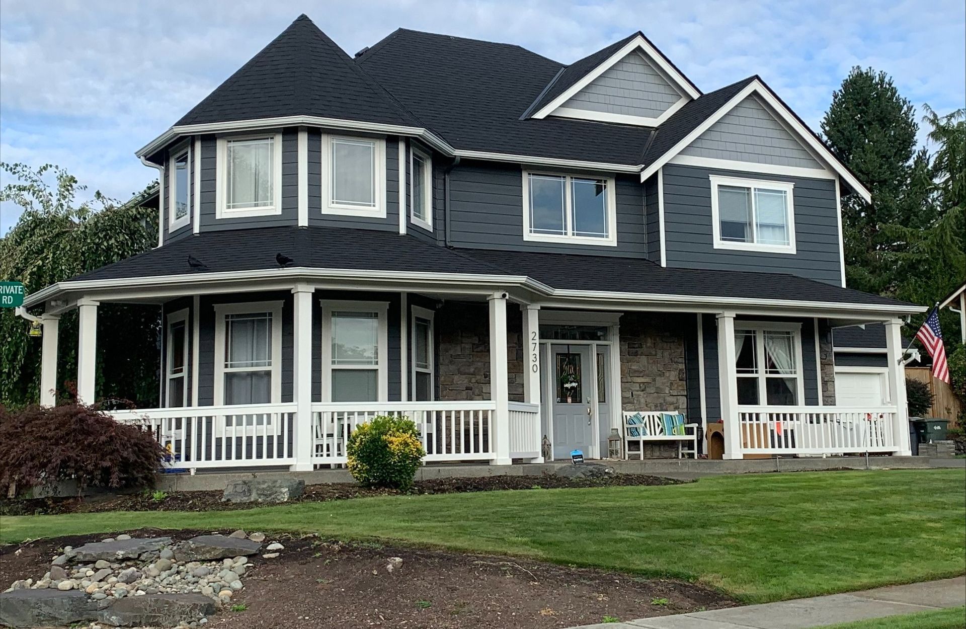 A large house with a black roof and a large porch.