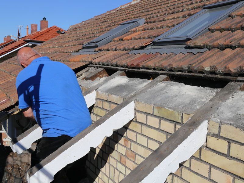 A man in a blue shirt is working on a roof