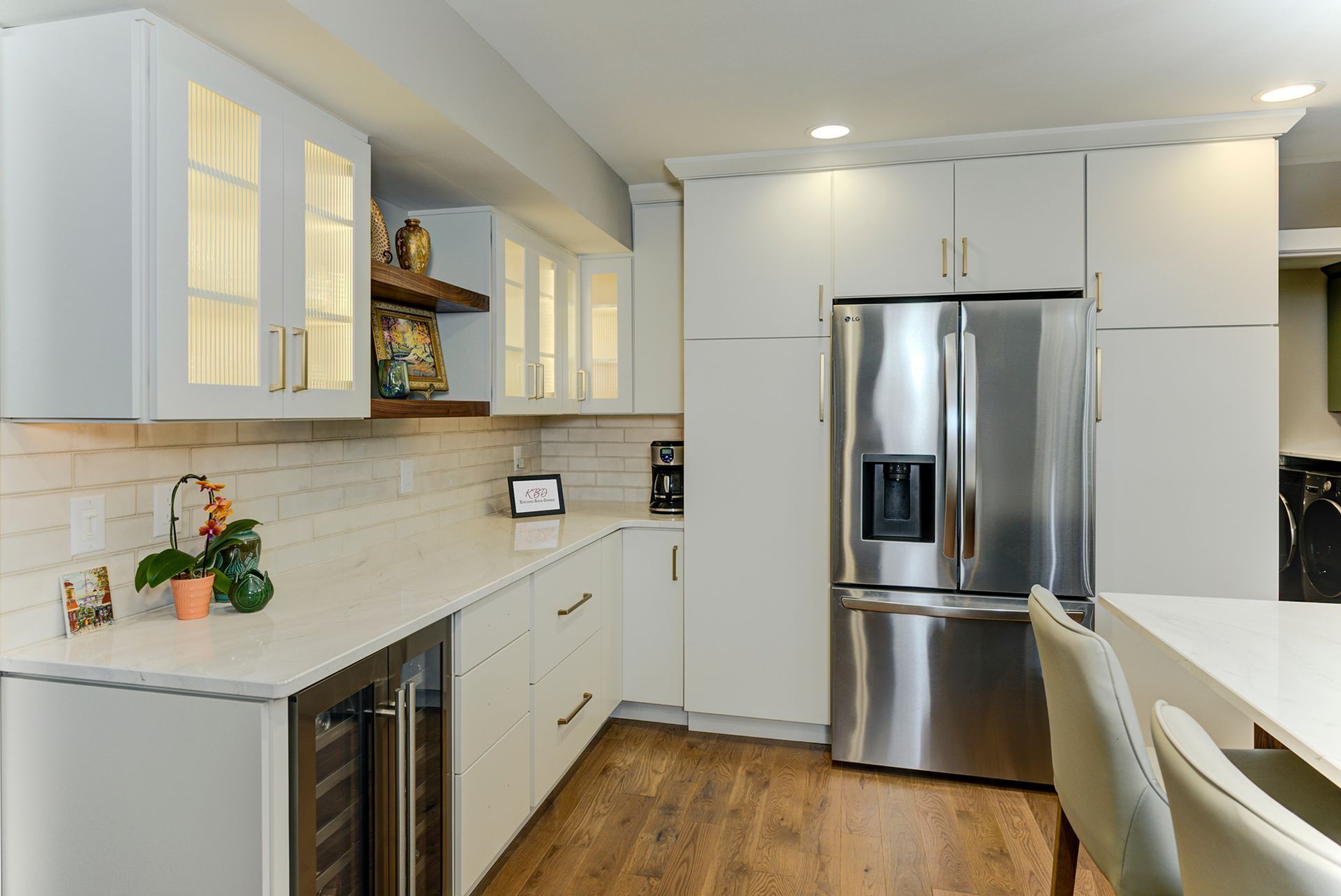 White kitchen with stainless steel fridge, white cabinets, and wooden floors.