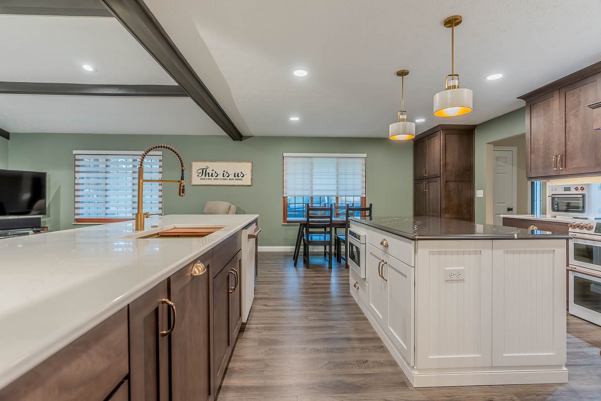 Kitchen with two islands, light countertops, dark cabinetry, and gold fixtures.