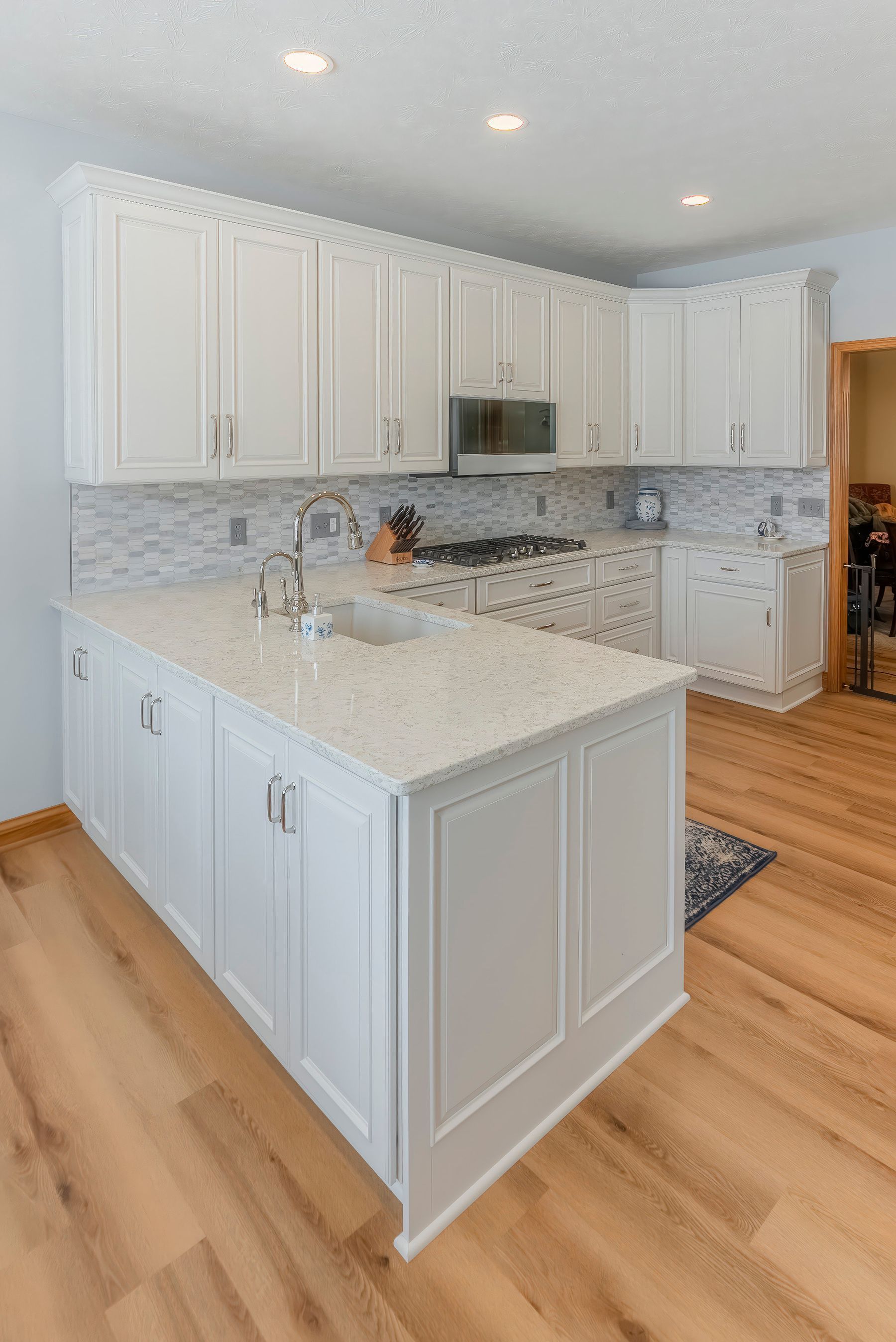 White kitchen with island, cabinets, countertops, and stainless steel appliances.
