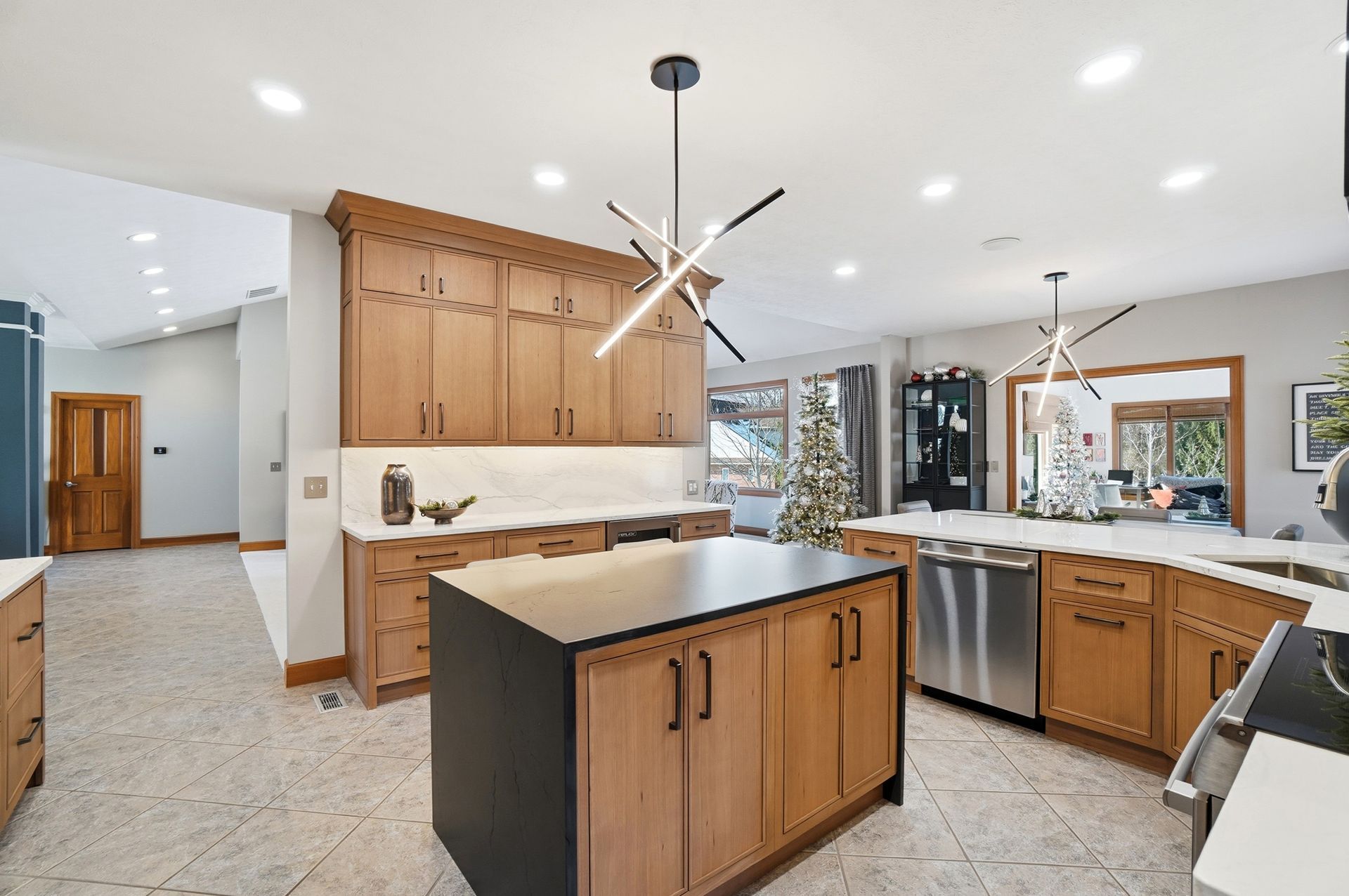 Modern kitchen with light wood cabinetry, a dark island, and a geometric light fixture.