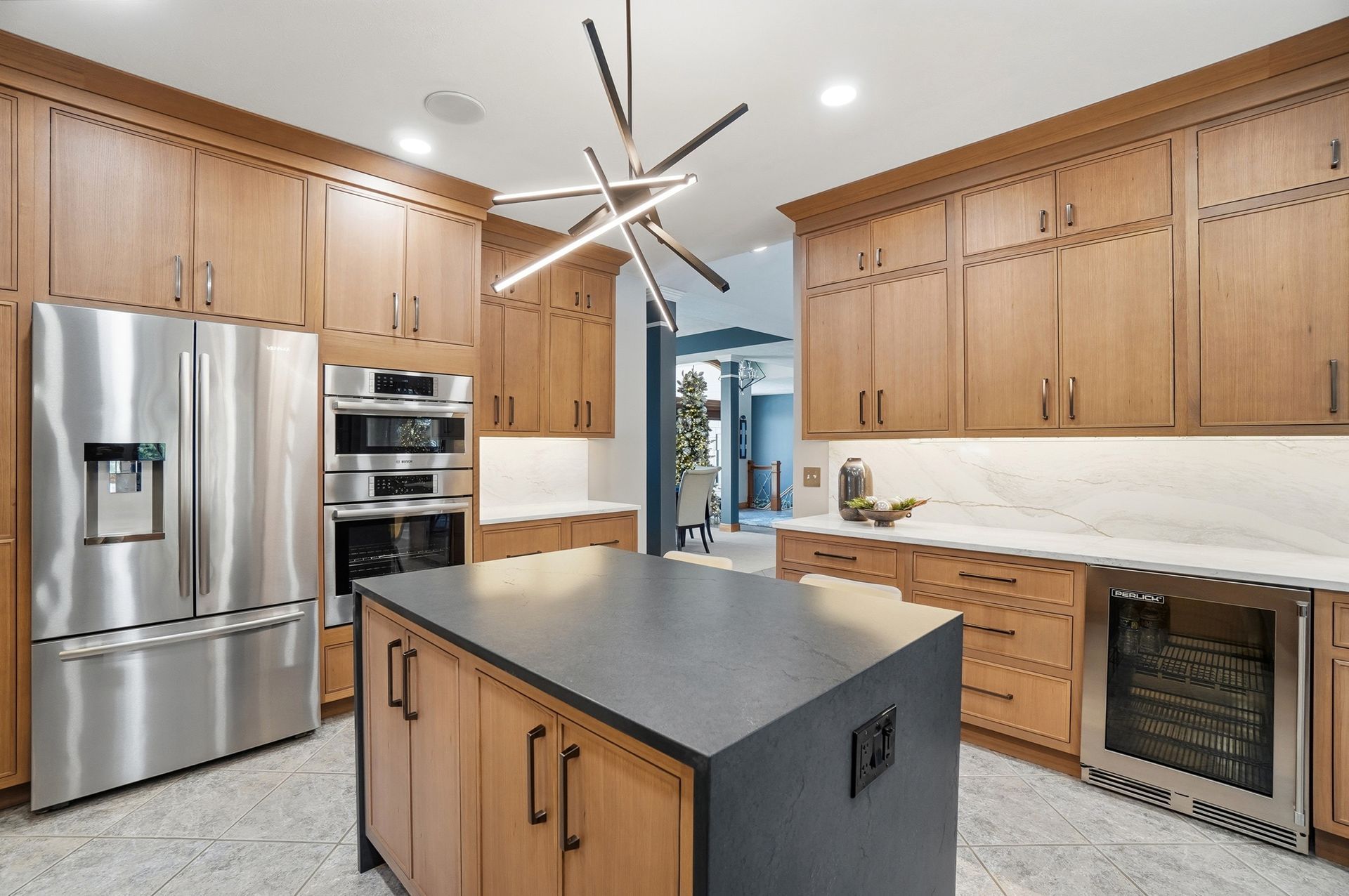 Modern kitchen with wooden cabinets, stainless steel appliances, and a dark island.