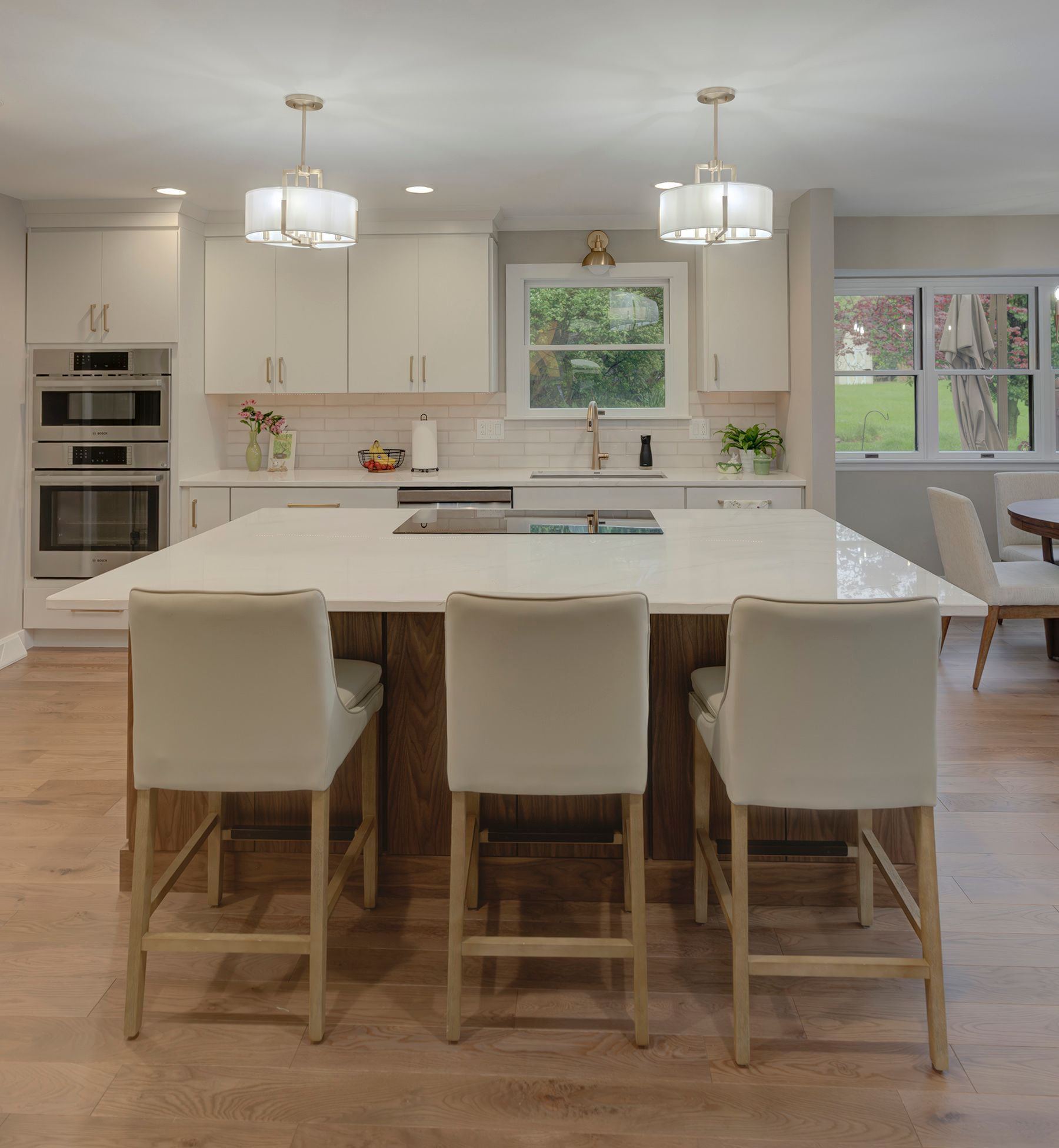 Modern kitchen with island, white cabinets, and three bar stools.