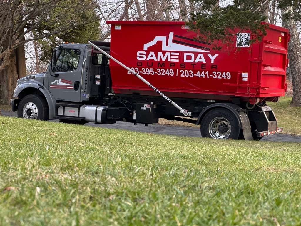 Gray dump truck parked outdoors near a metal structure.