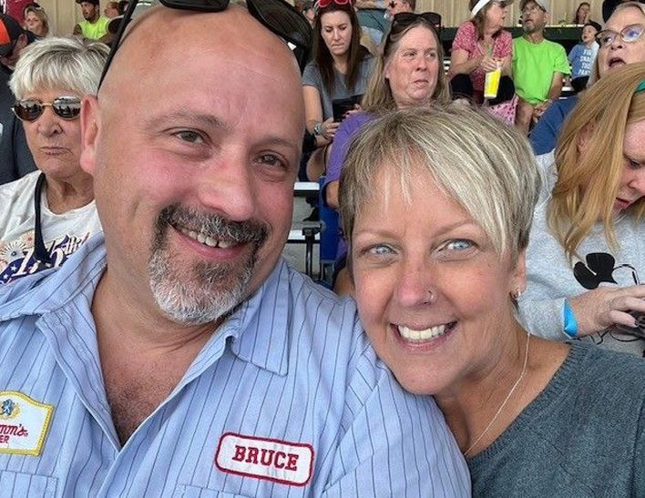 A man and woman are posing for a picture and the man has a name tag that says bruce