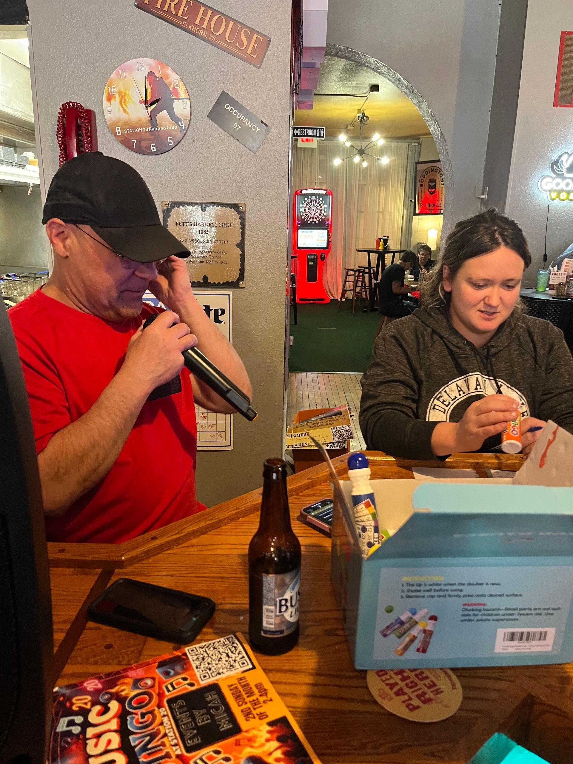 A man is singing into a microphone while a woman looks on.