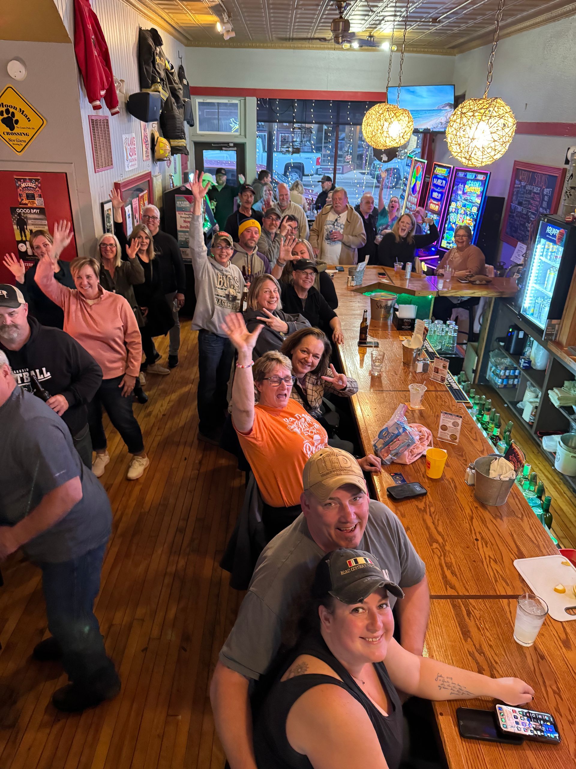 A group of people are standing around a bar in a restaurant.