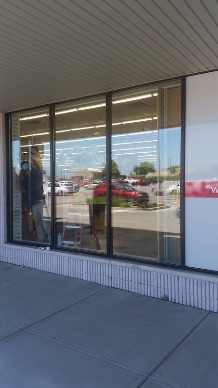 A man is standing in front of a store window.