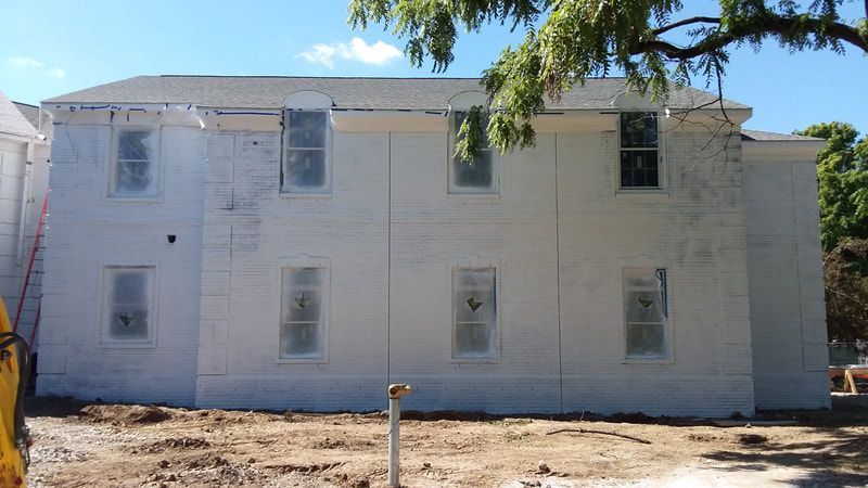 A large white building with a lot of windows is being painted.