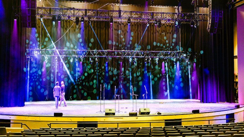 A couple of people standing on a stage with purple lights.