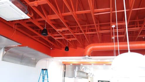 A red ceiling in a room with a ladder hanging from it.