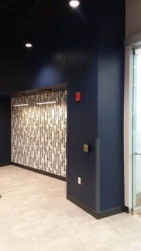 A hallway with blue walls and a fire alarm on the wall.