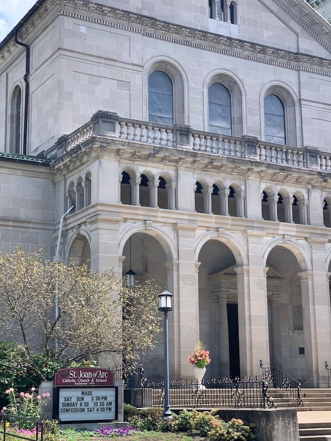 A large stone building with arches and a sign in front of it.