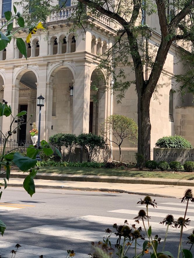 A large building with arches and a tree in front of it.