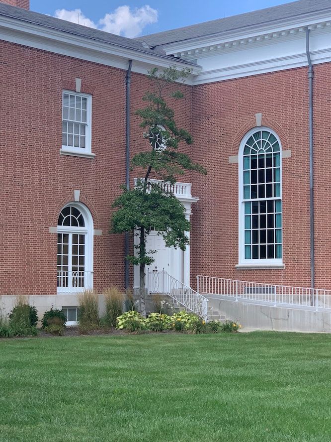 A large brick building with arched windows and a lush green lawn in front of it