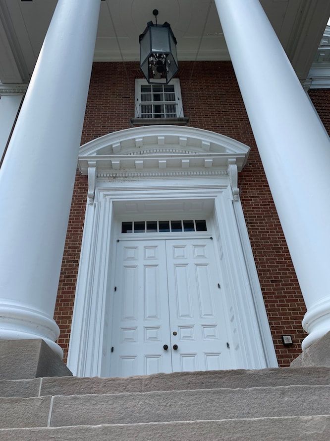 A brick building with white columns and a white door