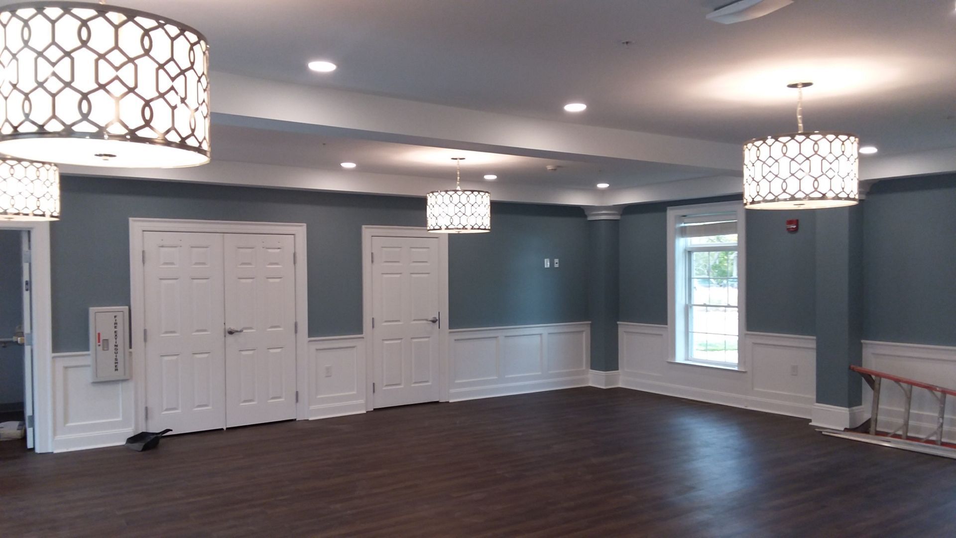A large empty room with a wooden floor and a lot of lights hanging from the ceiling.