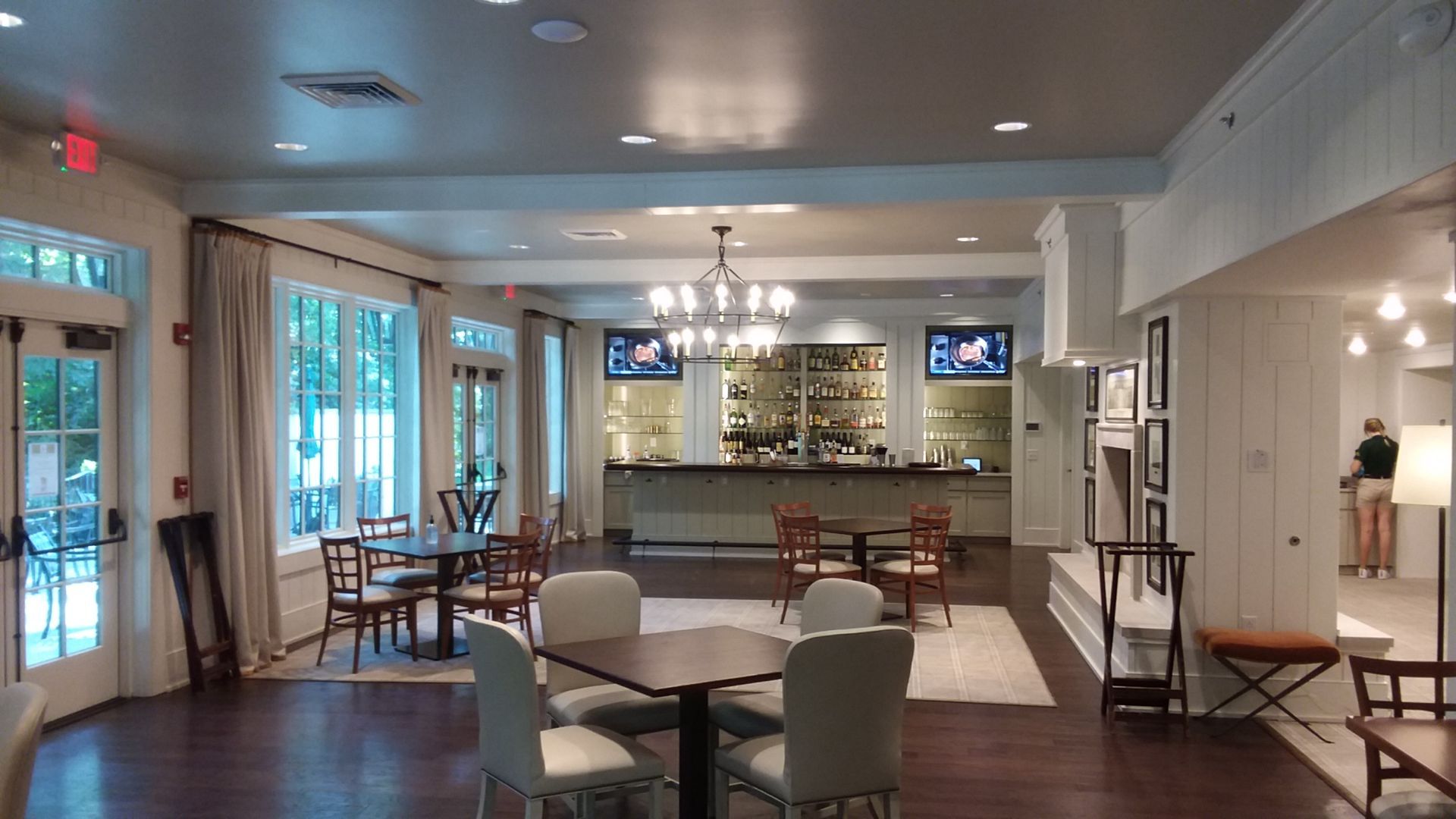 A large room with tables and chairs and a bar.