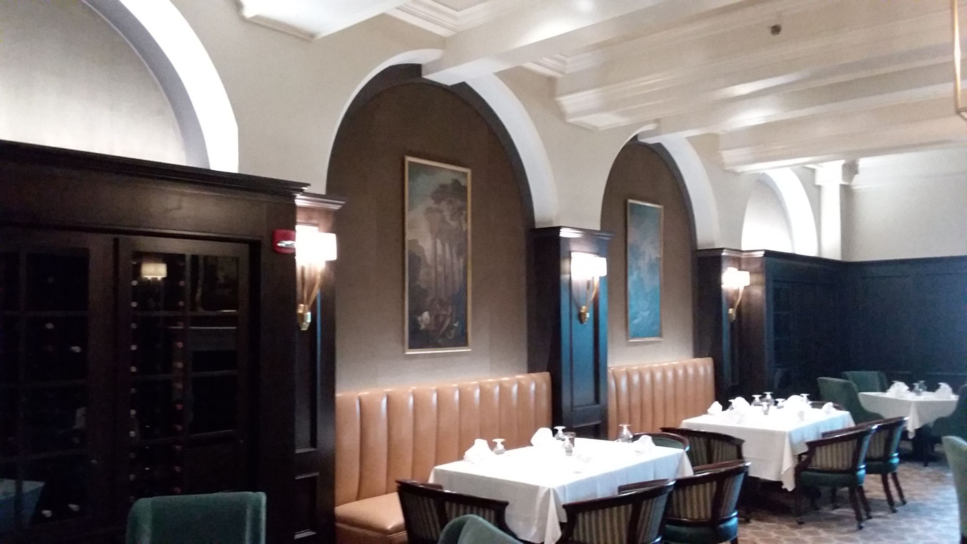 A dining room with tables and chairs and a painting on the wall