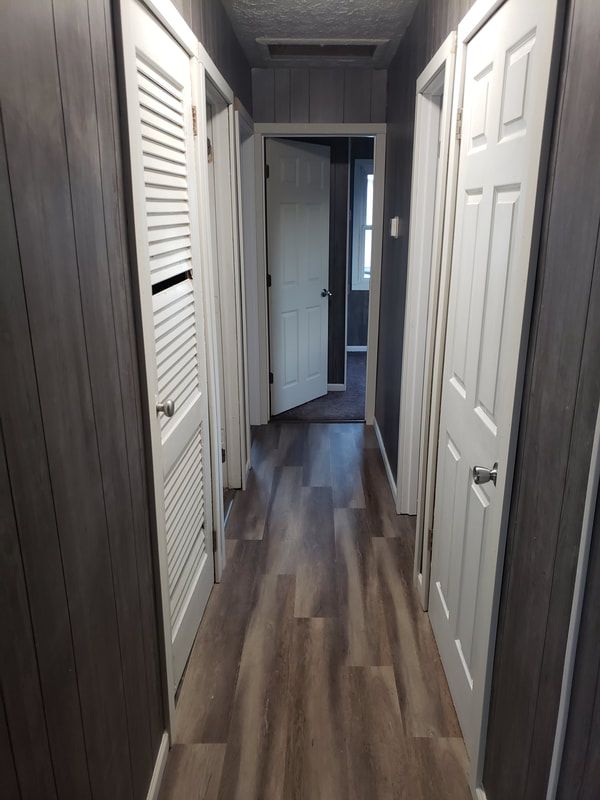 A hallway with hardwood floors and white doors in a house.