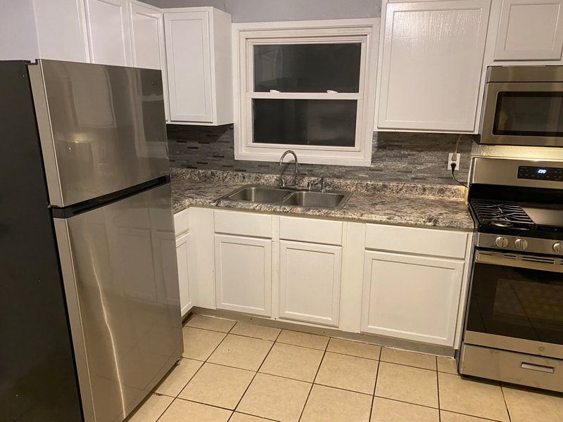 A kitchen with stainless steel appliances and white cabinets.