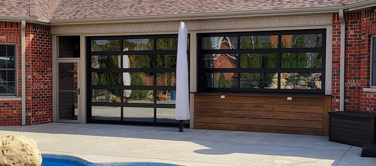 A brick building with a large garage door and a pool in the backyard.