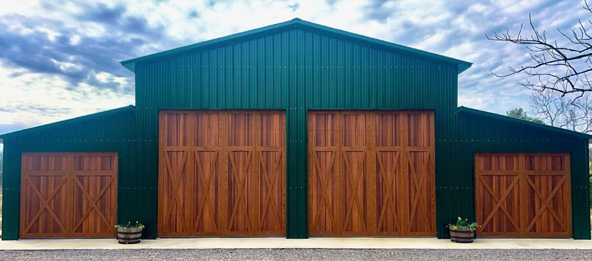 A green barn with wooden doors and a blue sky in the background.