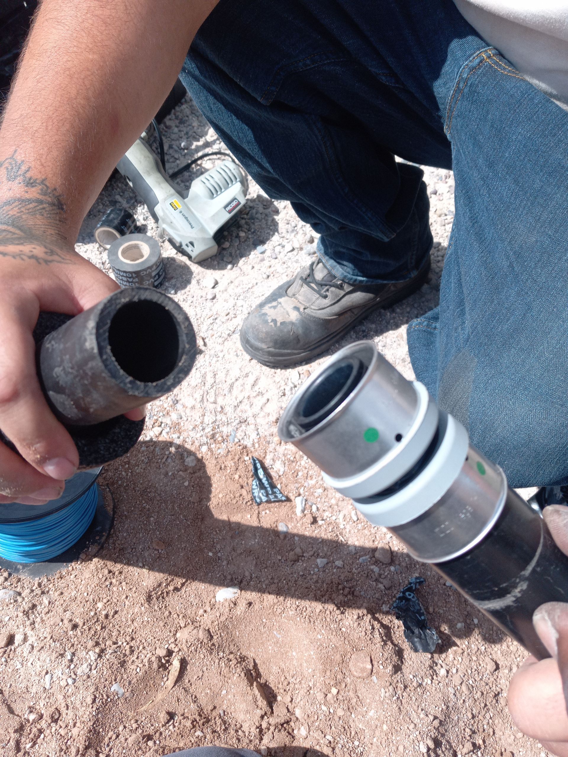 A man is working on a pipe in the dirt