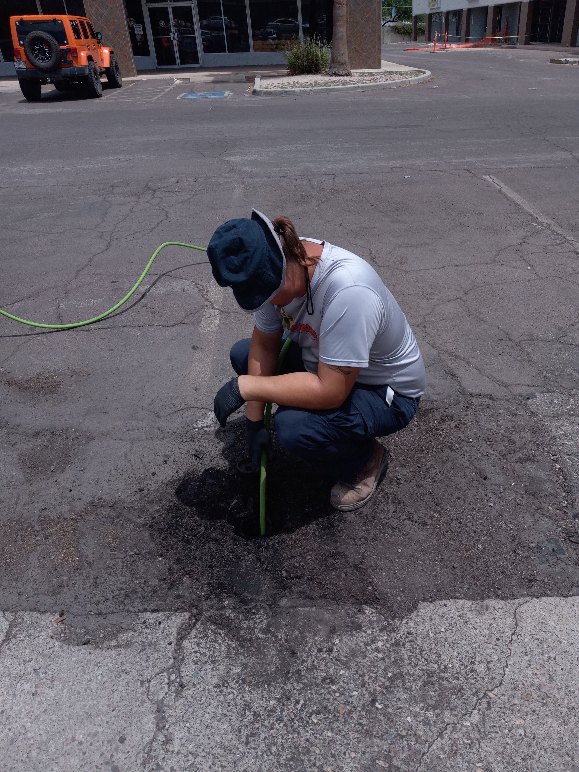 A man is measuring a hole in the ground with a tape measure.