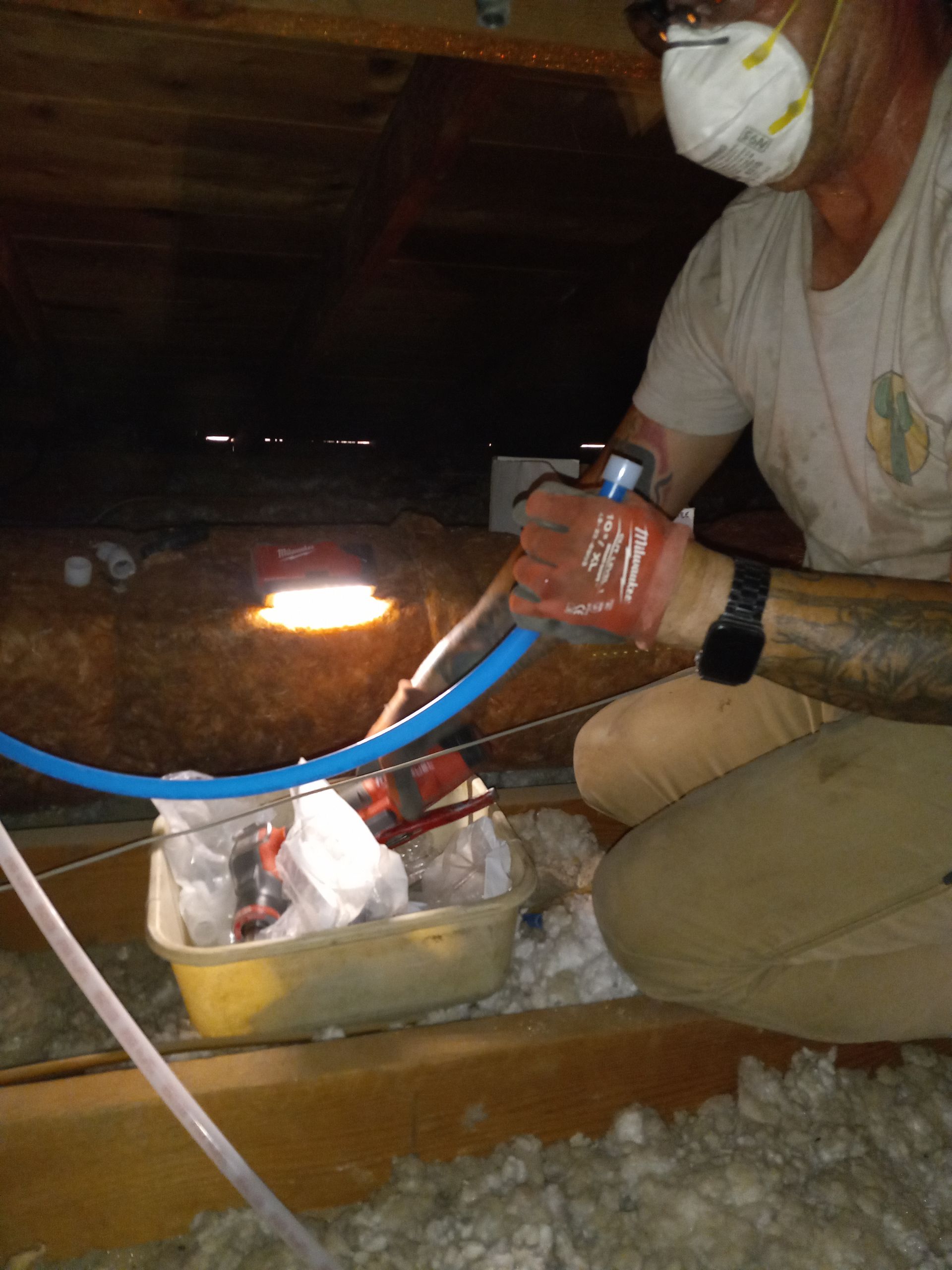 A man wearing a mask is working in an attic