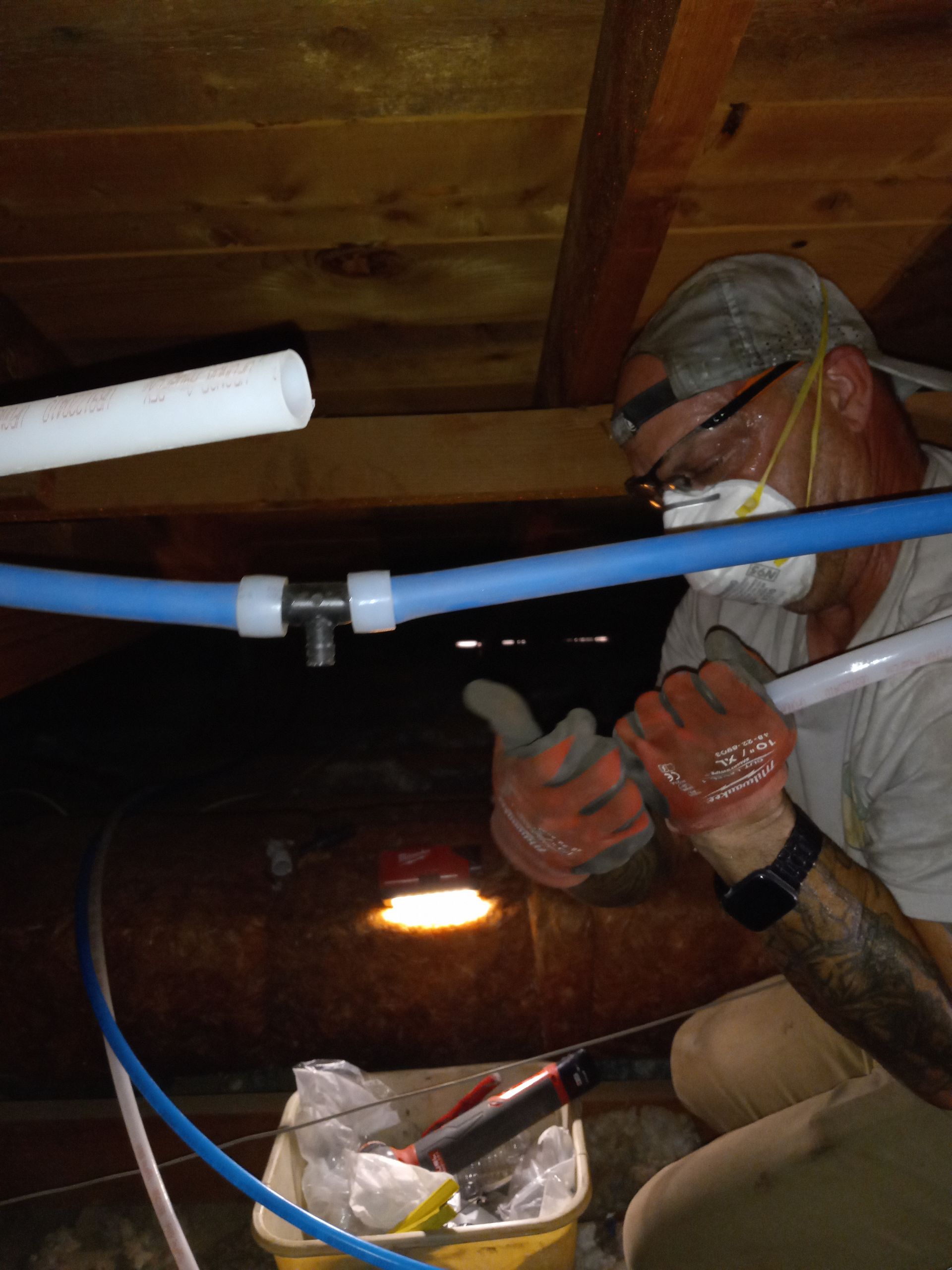 A man wearing a mask and gloves is working under a ceiling