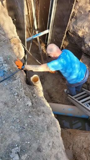 A man is standing on a ladder in a hole in the ground.