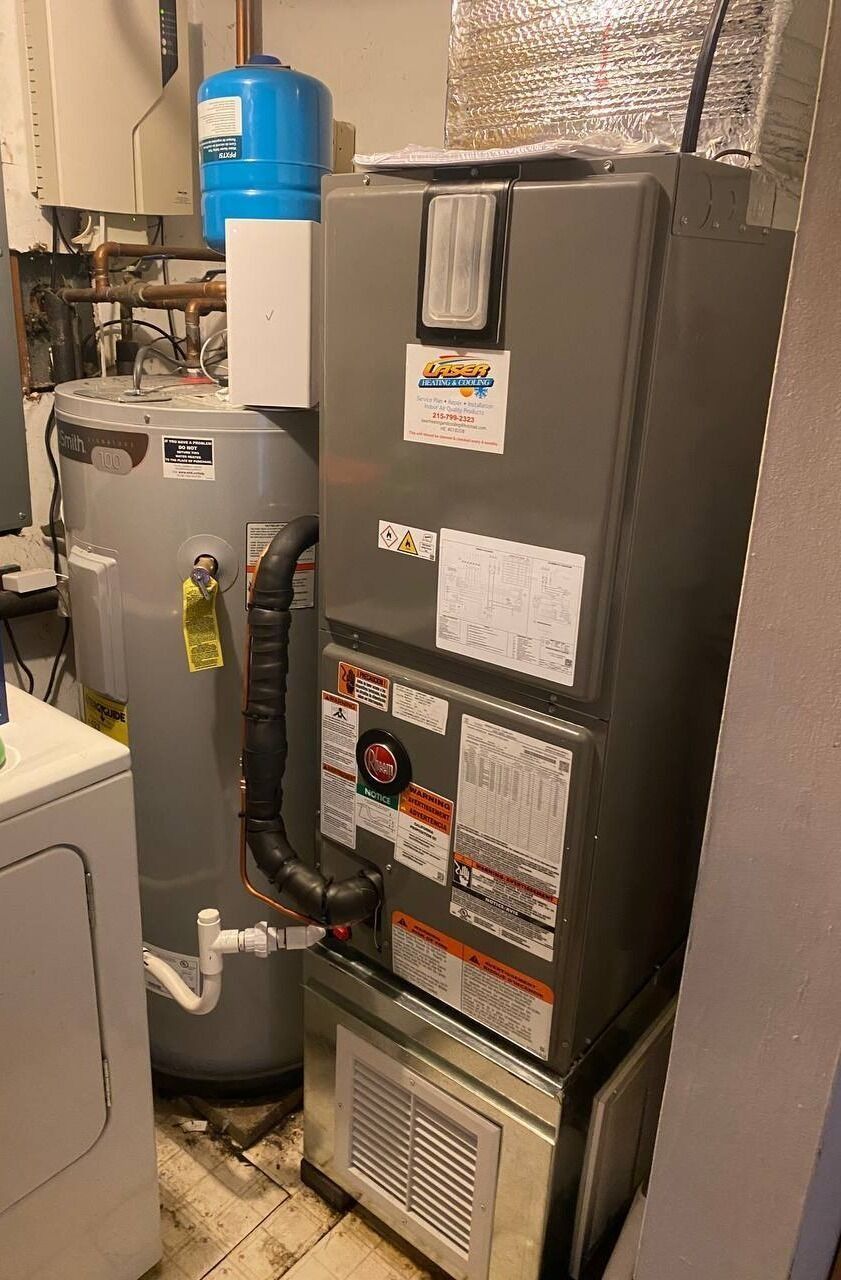 Furnace, water heater, and expansion tank in a utility room. Gray appliances on concrete floor.